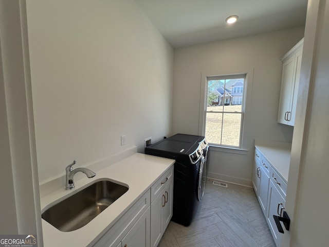 laundry area featuring cabinets, light parquet flooring, sink, and washer and dryer