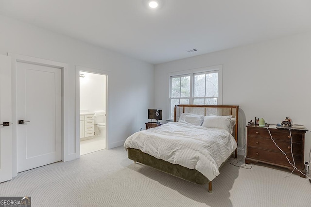 bedroom with connected bathroom and light colored carpet