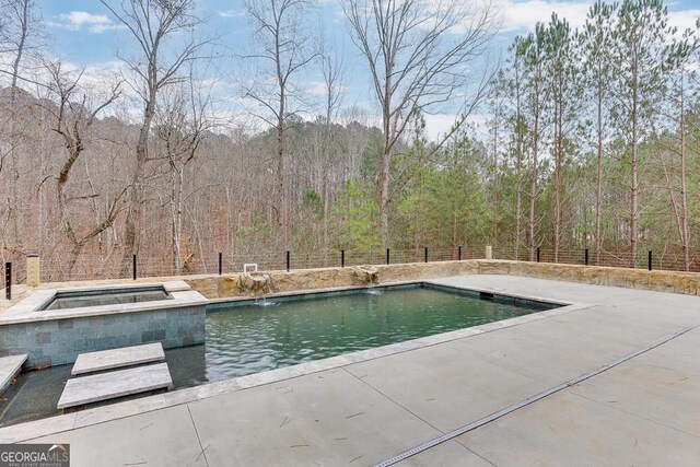 view of pool with an in ground hot tub, pool water feature, and a patio area