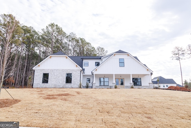 rear view of property featuring a yard and a porch