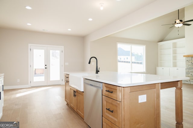 kitchen featuring a stone fireplace, dishwasher, an island with sink, sink, and french doors