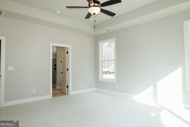 carpeted empty room featuring ceiling fan and a raised ceiling