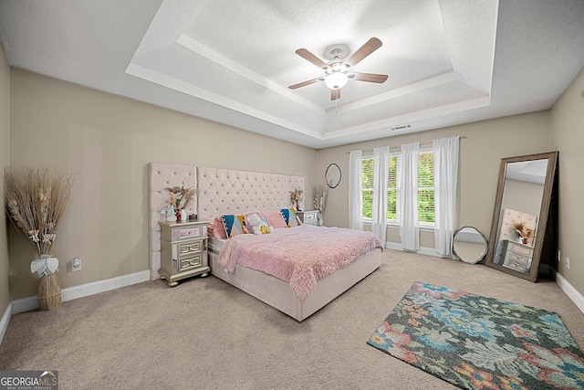 carpeted bedroom featuring a raised ceiling, ceiling fan, and a textured ceiling