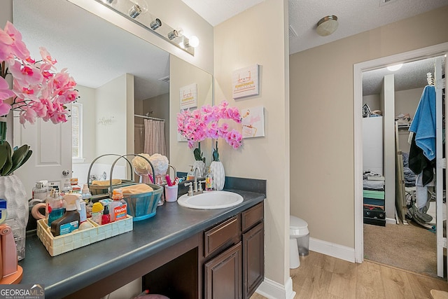 bathroom featuring hardwood / wood-style flooring, vanity, toilet, and a textured ceiling