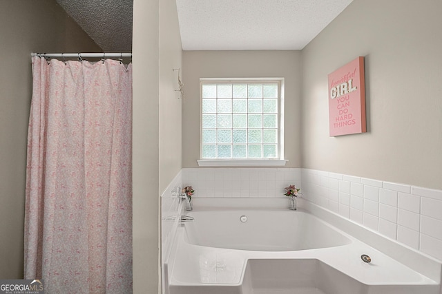 bathroom with a textured ceiling and a tub