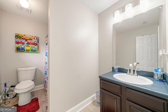 bathroom featuring vanity, hardwood / wood-style floors, a textured ceiling, and toilet