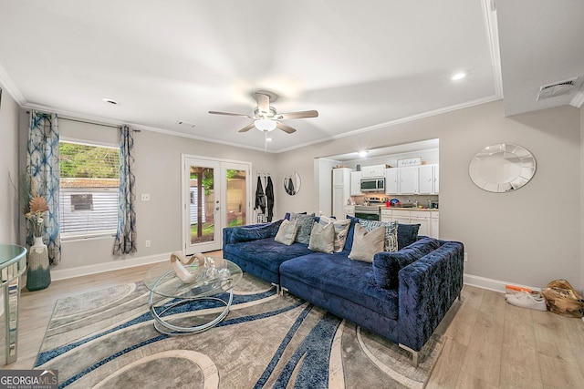 living room with ceiling fan, light wood-type flooring, crown molding, and french doors