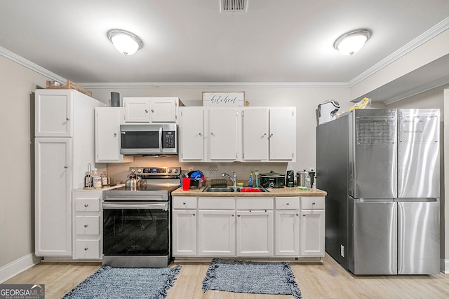 kitchen with sink, white cabinets, light hardwood / wood-style flooring, and appliances with stainless steel finishes