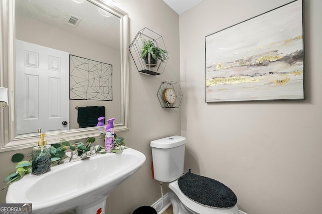 bathroom featuring a textured ceiling, toilet, and sink