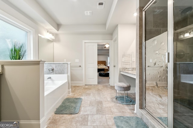 bathroom featuring a tray ceiling and independent shower and bath