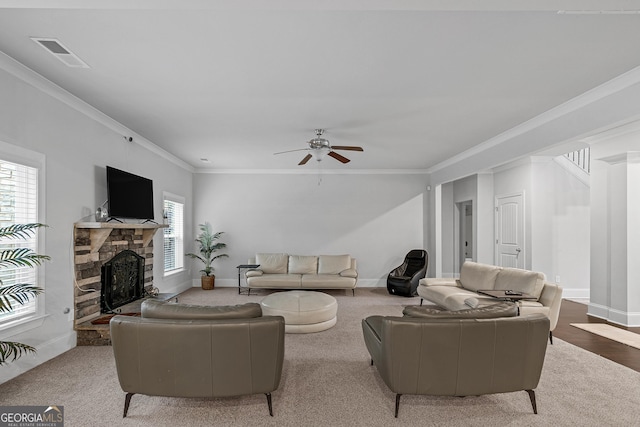 living room featuring light carpet, a stone fireplace, ceiling fan, and crown molding