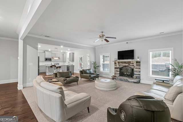 living room with ceiling fan, a fireplace, wood-type flooring, and ornamental molding