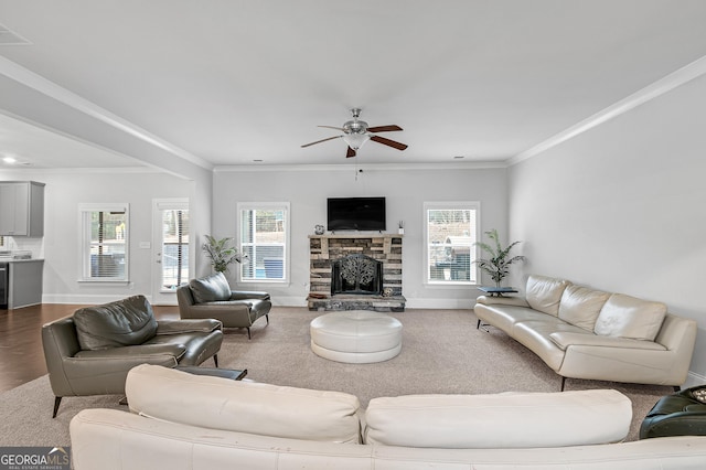 living room featuring plenty of natural light, ceiling fan, ornamental molding, and a fireplace