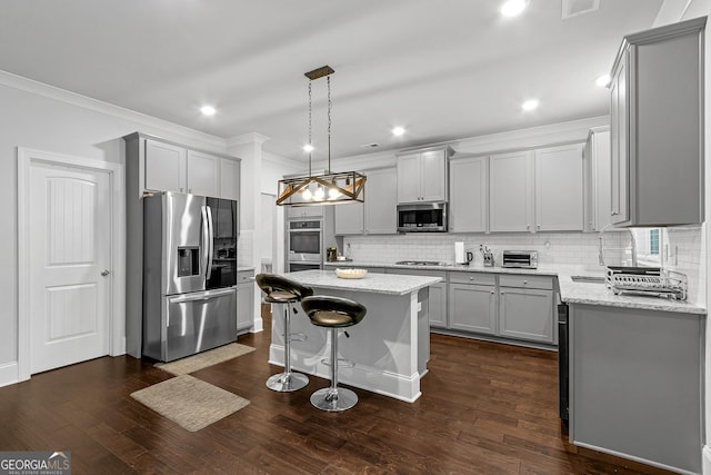 kitchen featuring gray cabinetry, light stone countertops, a center island, hanging light fixtures, and stainless steel appliances