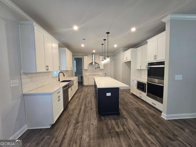 kitchen with white cabinets, appliances with stainless steel finishes, a kitchen island, and wall chimney range hood