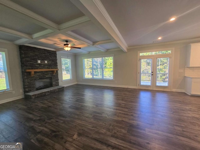 unfurnished living room with coffered ceiling, a stone fireplace, dark hardwood / wood-style floors, ceiling fan, and beam ceiling