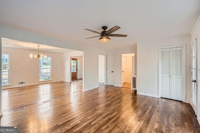 unfurnished living room with ceiling fan with notable chandelier, ornamental molding, and dark wood-type flooring