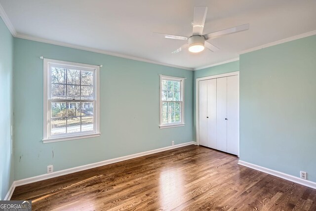 unfurnished bedroom with multiple windows, ceiling fan, a closet, and dark wood-type flooring