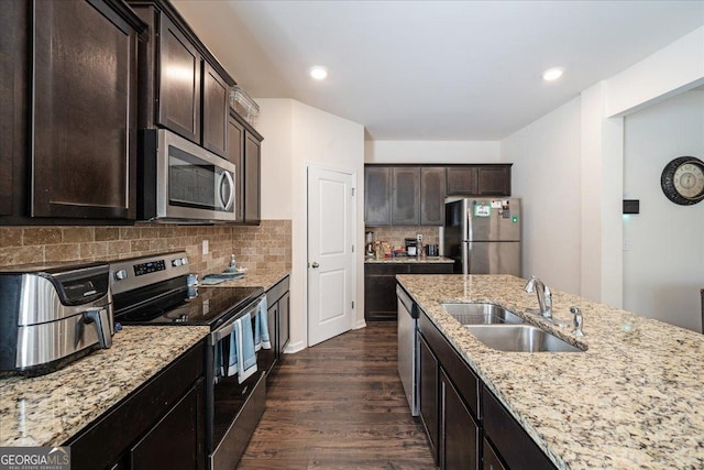 kitchen featuring sink, decorative backsplash, light stone counters, dark hardwood / wood-style flooring, and stainless steel appliances