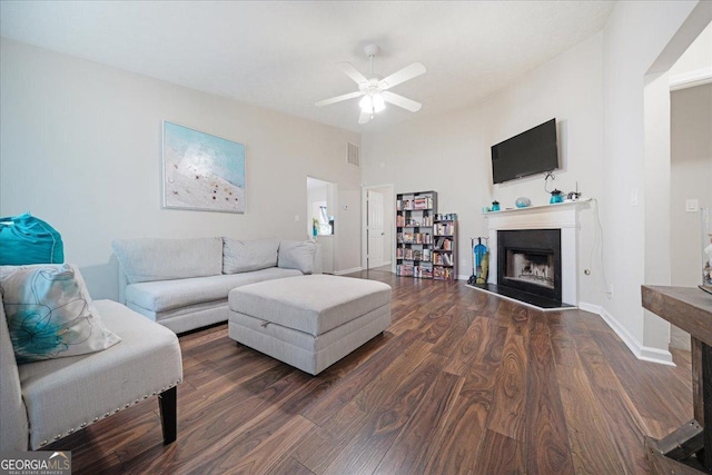 living room featuring ceiling fan and dark wood-type flooring