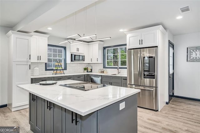 kitchen featuring pendant lighting, gray cabinets, light stone countertops, white cabinetry, and stainless steel appliances