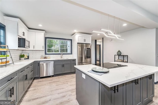 kitchen with white cabinetry, pendant lighting, a kitchen island, and stainless steel appliances