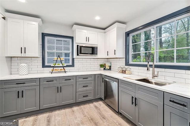 kitchen with built in microwave, dishwasher, white cabinets, and sink