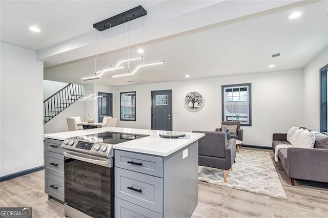 kitchen featuring pendant lighting, a center island, light hardwood / wood-style flooring, gray cabinets, and stainless steel electric range oven