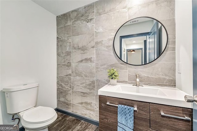 bathroom with vanity, tile walls, and toilet