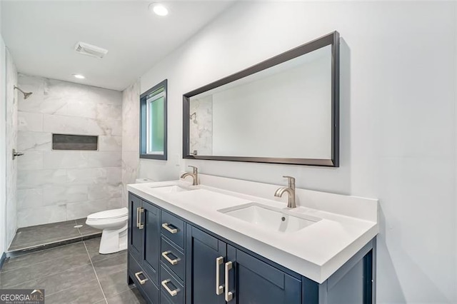 bathroom featuring a tile shower, vanity, and toilet