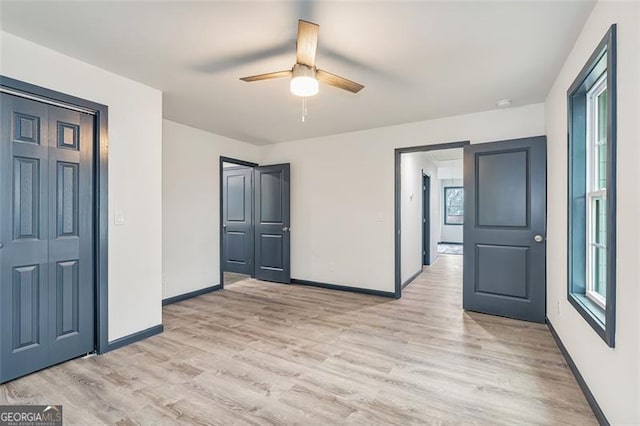 unfurnished bedroom featuring multiple windows, a closet, light hardwood / wood-style floors, and ceiling fan