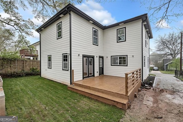 rear view of property featuring a lawn and a wooden deck