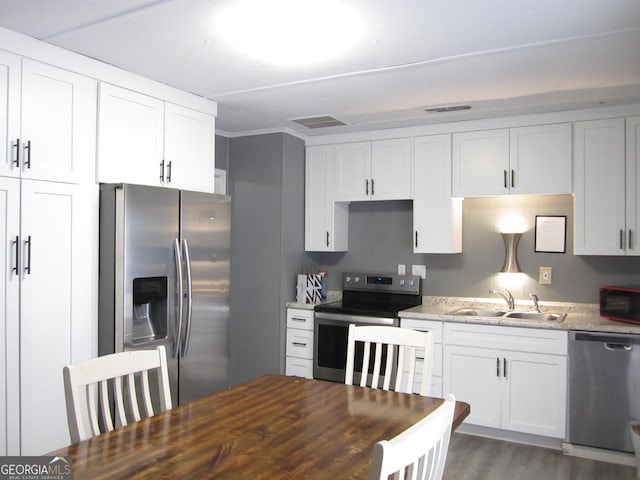 kitchen with white cabinets, sink, dark hardwood / wood-style floors, light stone counters, and stainless steel appliances