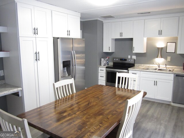 kitchen featuring light stone countertops, appliances with stainless steel finishes, dark wood-type flooring, sink, and white cabinets