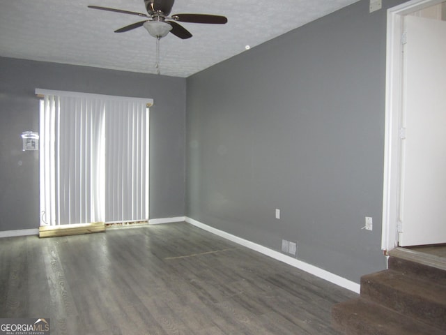 empty room featuring ceiling fan, dark wood-type flooring, and a textured ceiling