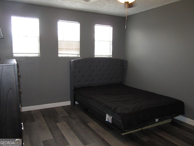 bedroom with a textured ceiling, washer / dryer, and dark wood-type flooring