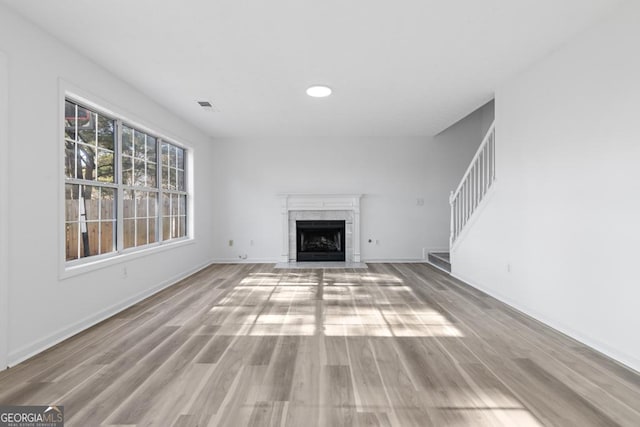 unfurnished living room featuring a high end fireplace and light wood-type flooring