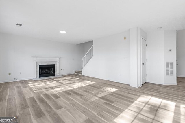 unfurnished living room with a tiled fireplace and light hardwood / wood-style floors