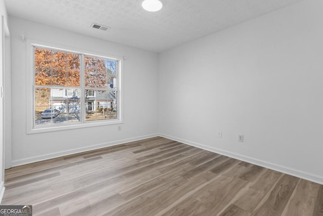 empty room featuring a textured ceiling and light wood-type flooring