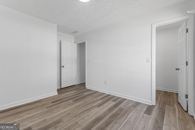 unfurnished room with light hardwood / wood-style floors and a textured ceiling