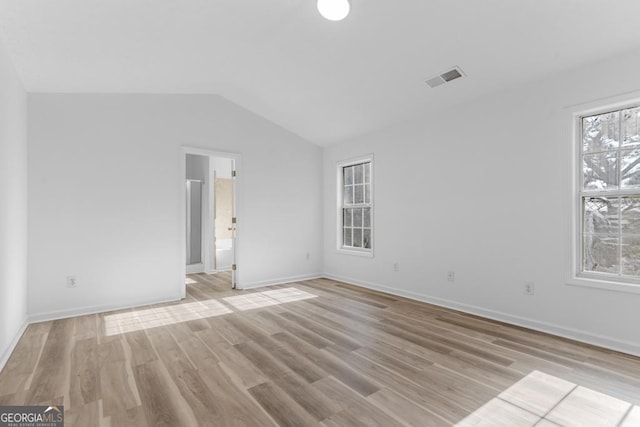 unfurnished room with a healthy amount of sunlight, vaulted ceiling, and light wood-type flooring