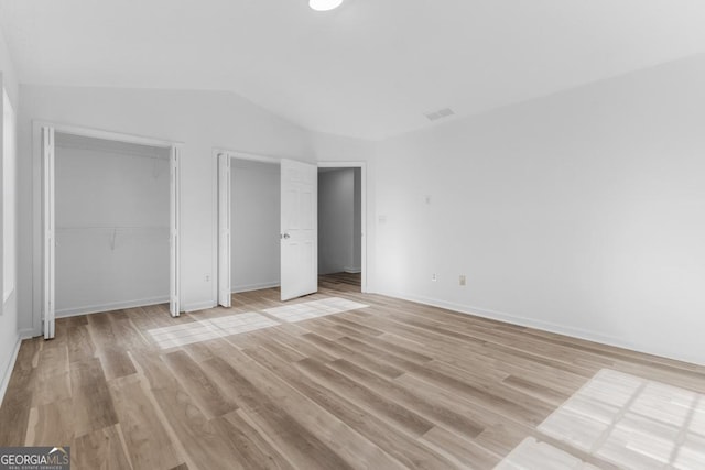 unfurnished bedroom featuring vaulted ceiling and light hardwood / wood-style flooring