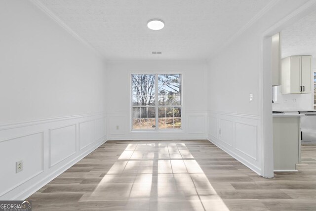 unfurnished dining area with light wood-type flooring and ornamental molding