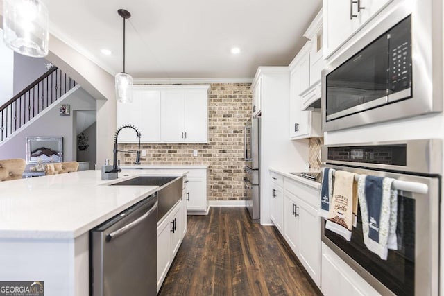 kitchen featuring a sink, white cabinets, light countertops, appliances with stainless steel finishes, and hanging light fixtures