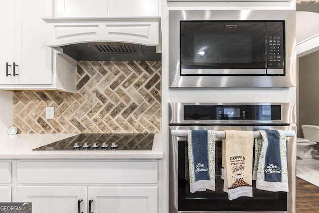 kitchen featuring tasteful backsplash, light countertops, custom range hood, appliances with stainless steel finishes, and white cabinets