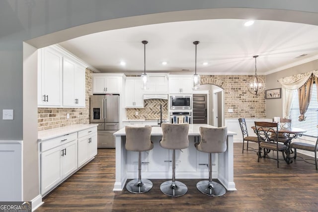 kitchen featuring stainless steel appliances, light countertops, white cabinets, and decorative light fixtures