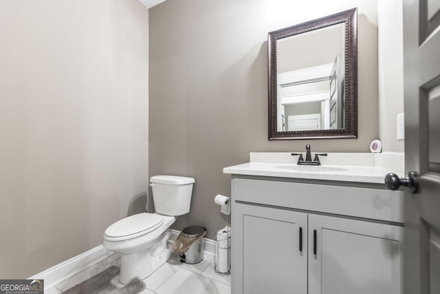 half bathroom with toilet, baseboards, and vanity