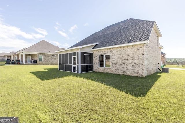 rear view of house featuring cooling unit, brick siding, a shingled roof, a sunroom, and a lawn