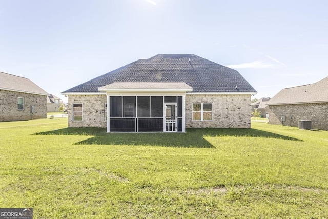 back of property with brick siding, a yard, central air condition unit, a shingled roof, and a sunroom