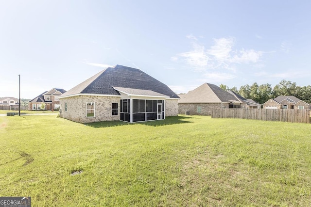 back of house featuring a residential view, a sunroom, a yard, and fence